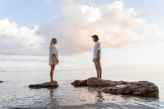 Young couple standing on rocks in front of the sea, Ibiza, Balearic Islands, Spain