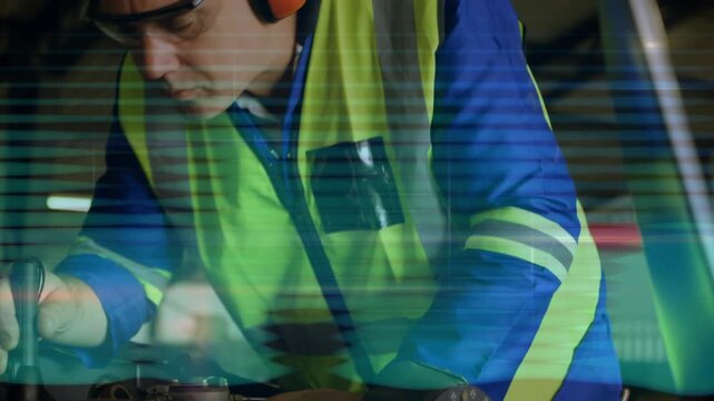 Vertical video: Maintenance tech repairing wiring using rotary tool in hangar camera pulling back