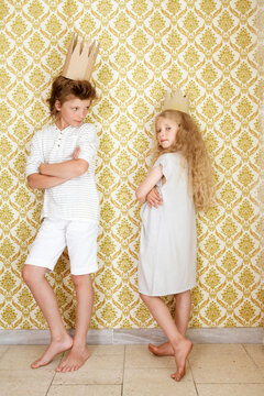 Boy and girl standing at a wall wearing cardboard crowns