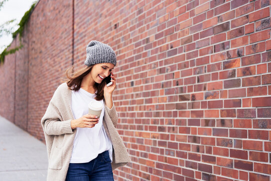 Happy woman with coffee to go on the phone