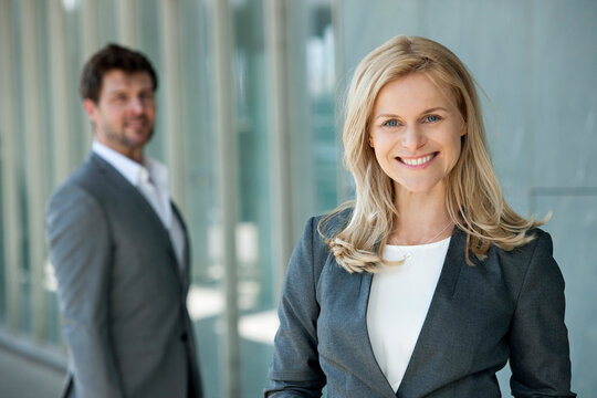 Portrait of smiling businesswoman with her partner watching in the background
