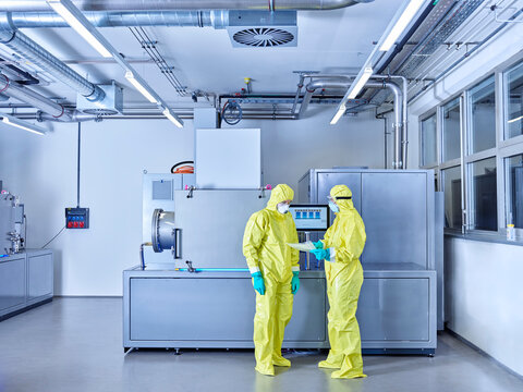 Chemists working in industrial laboratory, wearing protective clothing in the clean room