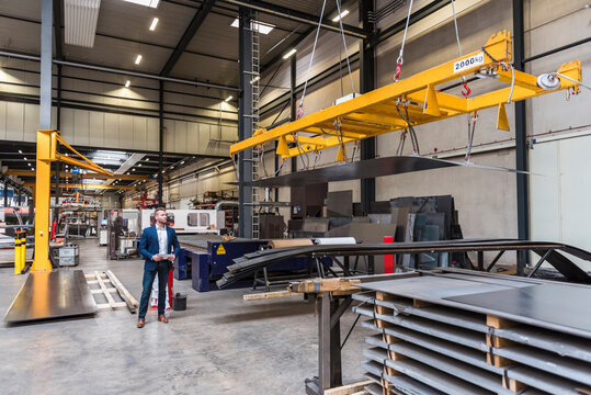 Businessman with tablet standing on factory shop floor