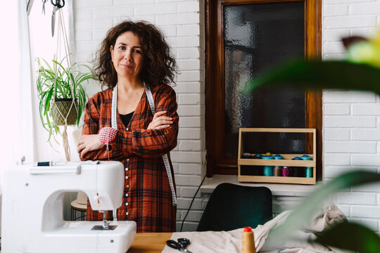 Portrait of confident woman with sewing machine at home