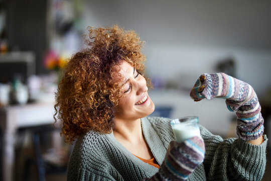 Happy woman playing with hand doll, holding glass of milk
