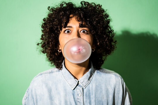 Portrait of young woman blowing bubble gum bubble