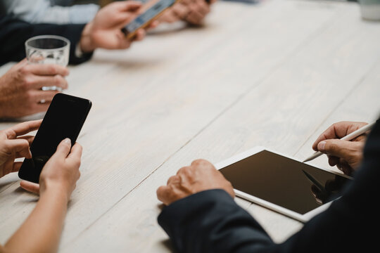 Business people working in office using portable devices, close up