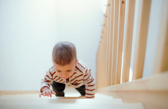 Toddler boy climbing up stairs at home