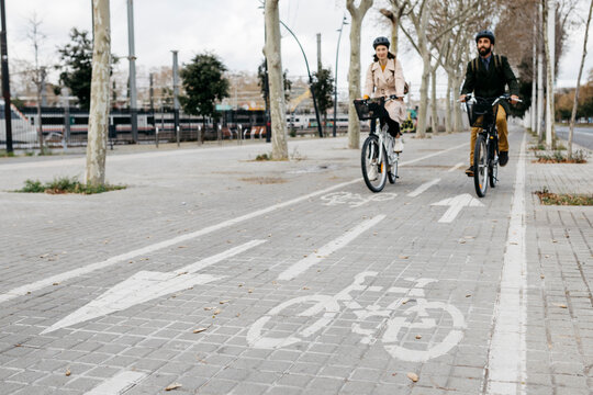 Couple riding e-bikes in the city on bicycle lane