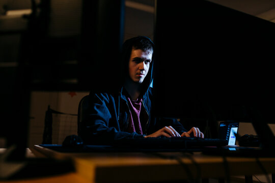 Young hacker working on computer while sitting at office