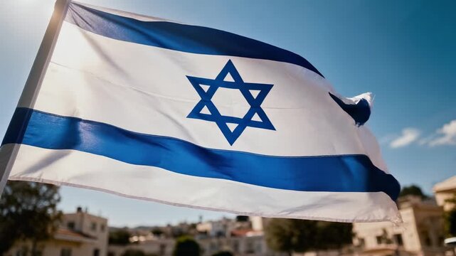 Waving Israeli flag with Star of David under clear blue sky over city buildings