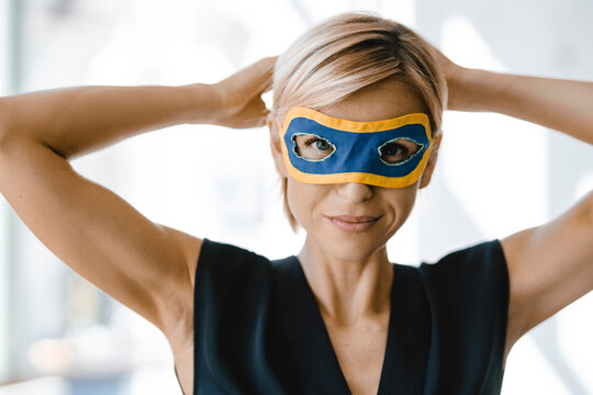 Portrait of blond businesswoman, wearing superwoman mask