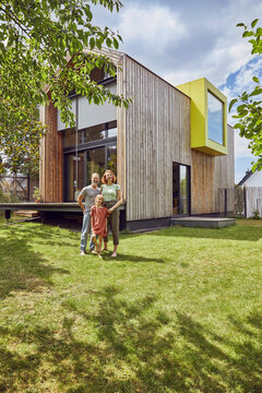 Family standing on grassy land in front of tiny house