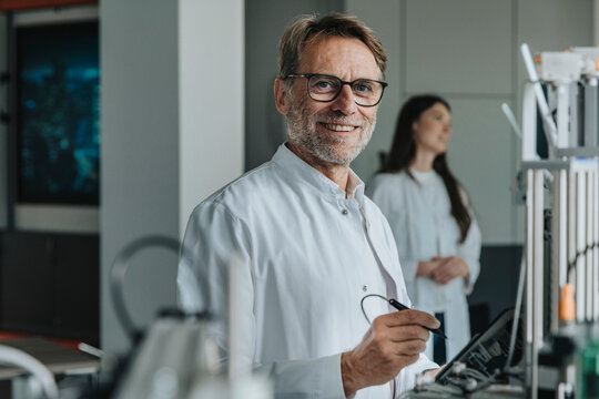 Scientist inventing machinery with female colleague in background at laboratory