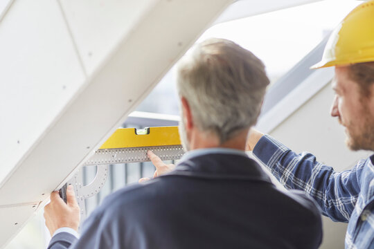 Architect and worker measuring window on a construction site
