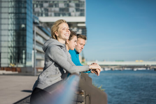Friends leaning on railing at the riverside after training