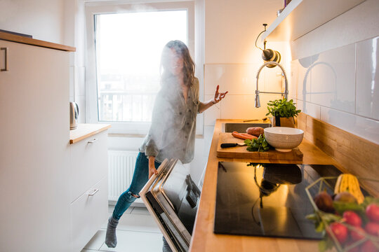 Woman opening steaming dish washer in the kitchen