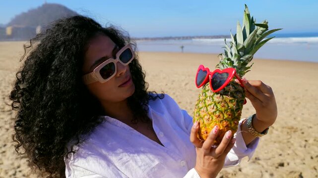 Stylish woman having fun with pineapple friend at the beach