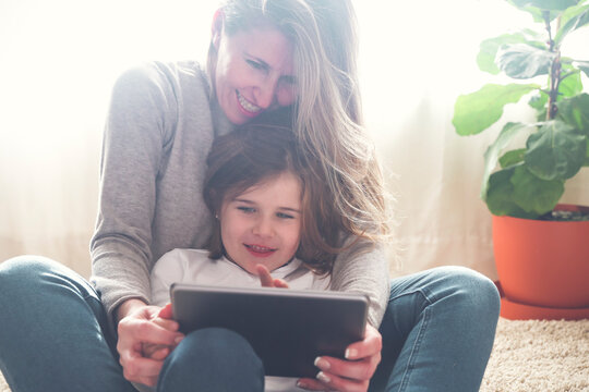 Mother and little daughter using tablet at home