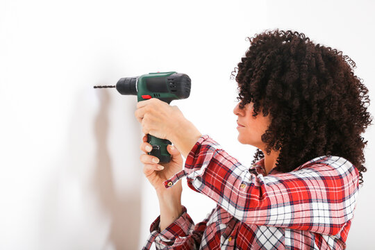 Woman using portable drill, marking with pencil on a wall