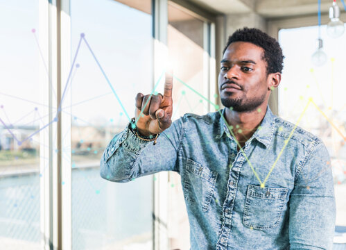 Casual businessman touching glass pane with diagram in office