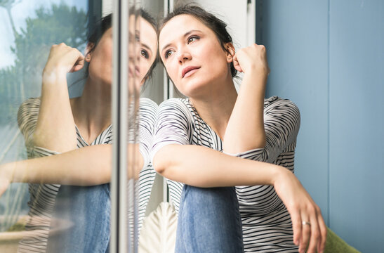 Serious woman looking out of window at home