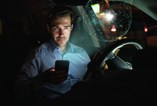 Businessman using smartphone in car at night surrounded by virtual shining globe