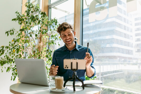 Young businessman smiling while discussing on video call at table in cafe