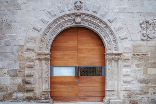 Modern Wooden Door In Ancient Stone Archway, Plateresque Style Carved Reliefs, Building Facade