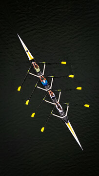 Aerial view of a sleek rowing boat cutting through the dark waters, its yellow-tipped oars flashing like gold, Divonne-les-Bains, Auvergne-Rhone-Alpes, France.