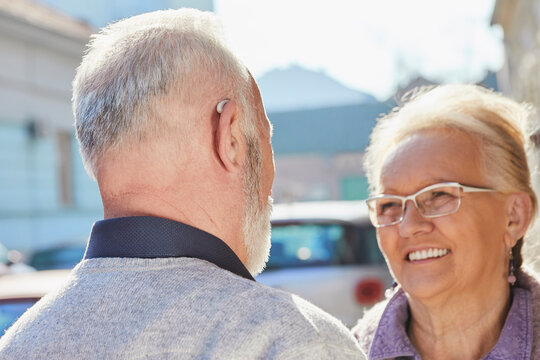 Close-up of senior man with hearing aid talking to senior woman
