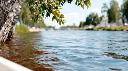 Naklejka premium A serene riverside scene with gently flowing water under vivid blue skies, reflecting nature's beauty and tranquility, inviting calmness and relaxation to viewers.