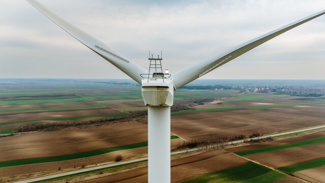 Aerial view of the colossal wind turbine standing tall against the patterned agricultural fields, a beacon of renewable energy, Alibunar, Vojvodina, Serbia.