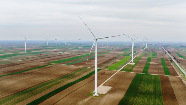 Aerial view of wind turbines stand tall amidst the patchwork of agricultural fields, creating a striking contrast between modern energy and rural landscape, Alibunar, Vojvodina, Serbia.