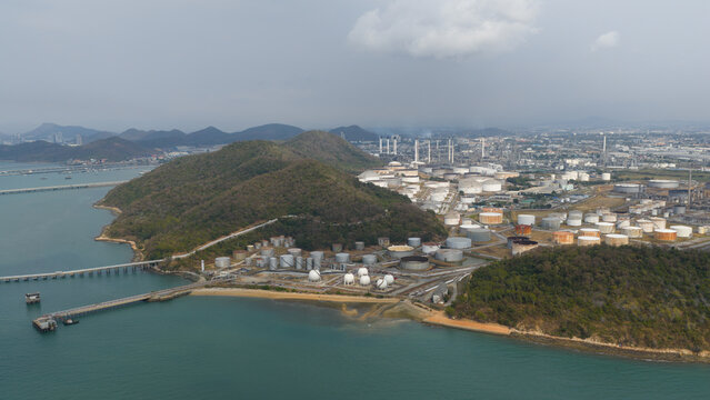 Aerial view of industrial tanks clustered near the forested hills meeting the sea, Laem Chabang, Thailand.