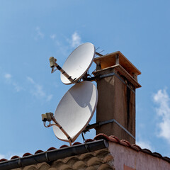 Petite et grande paraboles fix&eacute;es contre une chemin&eacute;e