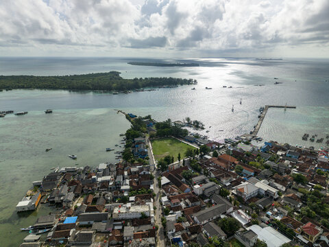 Aerial view of the town square blending into the sea with boats dotting the horizon under a sky streaked with clouds, Karimunjawa, Central Java, Indonesia.