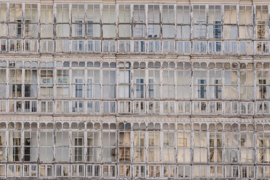 View of a building facade with numerous glass-enclosed balconies reflecting light and shadow, creating a textured, patterned architectural vista, Burgos, Burgos, Spain.