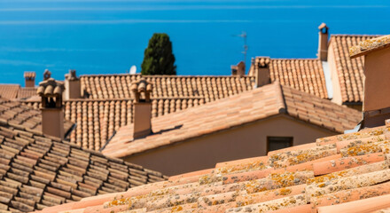 Mediterranean old town architecture with terracotta roof tiles and ancient chimneys under a clear blue sky, evoking a classic european travel scene.