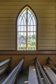 View of light streaming through an arched window onto wooden pews, casting shadows in the church interior, Utvik, Vestland, Norway.
