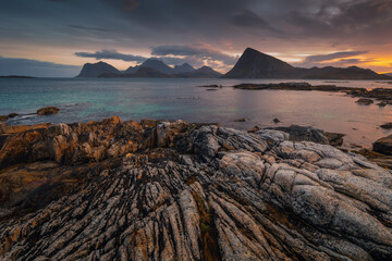 Stunning fall scenery in the Lofoten Islands. Iconic red rorbu cabins nestled between rocky coastlines and dark arctic waters during the golden hour. Travel Norway. © PawelUchorczak