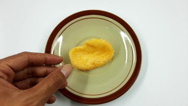 Hand placing crunchy prawn cracker onto small traditional plate footage