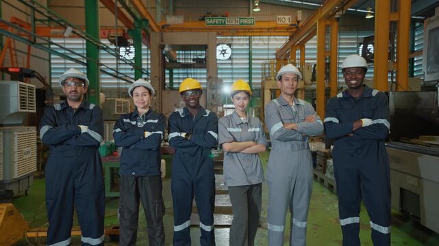 Team of multi-ethnic mechanical technicians or engineers arms crossed confidently in a medium-sized automotive parts manufacturing factory, representing a globally standardized quality team.