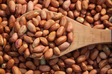 Obraz premium red peeled peanuts in wooden spoon texture background. 