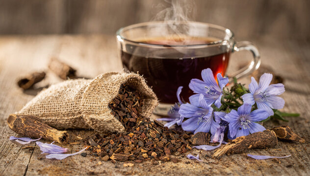 Steaming herbal coffee, chicory root, flower on rustic wood. Natural remedy
