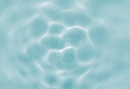 Sunlit turquoise water surface with soft circular ripple light reflections
