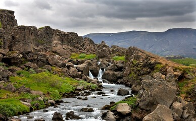 Fototapeta premium Thingvellir - Iceland Panoramic view of Thingvellir, Iceland, showcasing a dramatic landscape with rocky cliffs and expansive grassy plains.