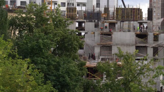 Summer day at construction site with crane lifting concrete slabs.
