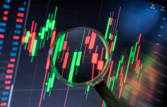 Magnifying glass over stock market trading graph on computer screen