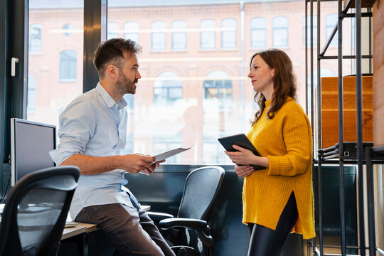 Colleagues discussing work in a modern office with tablets